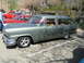 1973 Ford Ranchero - A green station wagon with custom wheels is parked at a car show next to a red pickup truck.