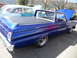 1973 Ford Ranchero - A blue pickup truck is parked next to a light blue sedan with a 'For Sale' sign in the window.