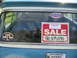 1973 Ford Ranchero - A "For Sale" sign with a phone number is displayed on the rear window of a vehicle, alongside various stickers.