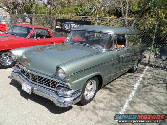 Green 1956 Ford Fairlane wagon parked next to a red pickup truck