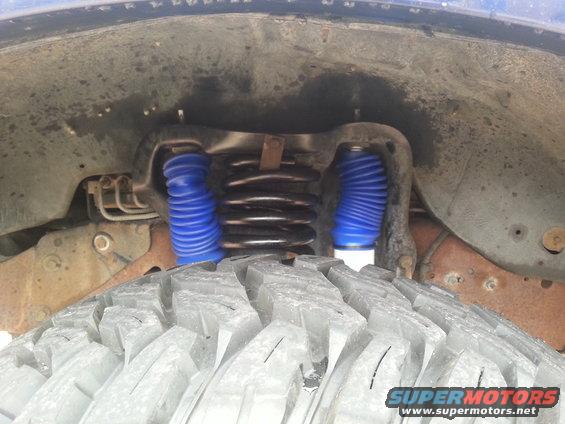 Close-up of front suspension with blue shock boots and coil spring