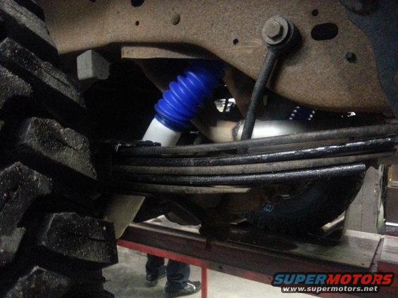 Close-up of a large tire and suspension system with a blue shock absorber boot