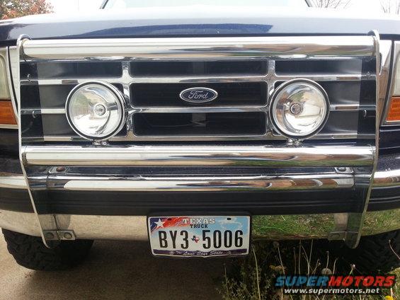 Dark blue Ford Bronco front grille with chrome bull bar and two round fog lights. Texas license plate BY3 5006