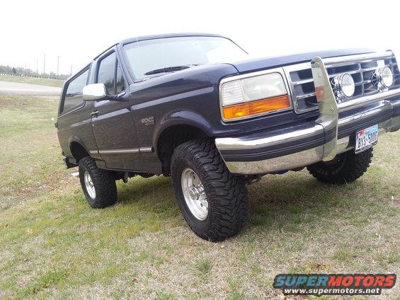 1995 Ford Bronco with aftermarket grille guard and off-road tires parked on grass