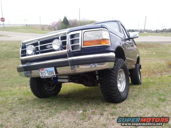 Dark blue Ford Bronco with lifted suspension and large tires, viewed from a low front 3/4 angle