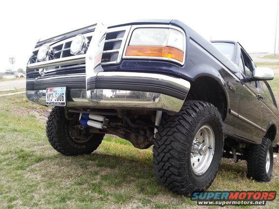 Blue Ford Bronco with a brush guard and lifted suspension. License plate reads 8Y3-5006
