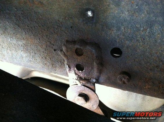 Close-up of rusted vehicle frame showing a mounting bracket and bolt