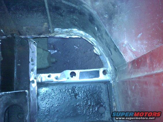 Red vehicle interior showing rust repair on wheel well and floor pan