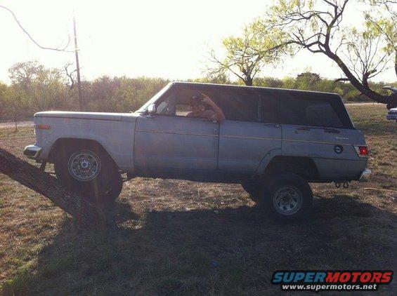 Gray 1982 Jeep Wagoneer side view, front tire on tree trunk