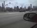 2003 Ford Crown Victoria - A dark sedan drives along a road with the Chicago skyline visible under a cloudy sky.