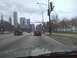 2003 Ford Crown Victoria - A red 2003 Ford Crown Victoria is seen from behind driving on a multi-lane road with city buildings in the background.