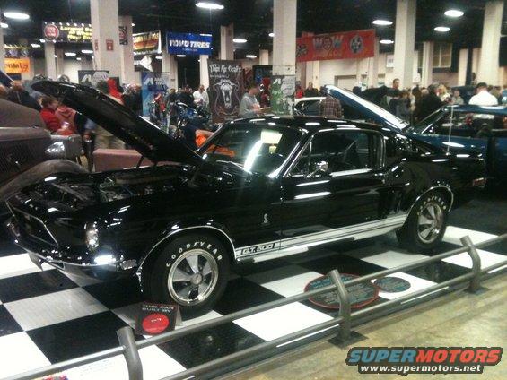 Black 1967 Ford Mustang GT500 with hood and trunk open, displayed indoors