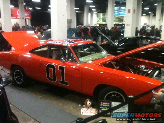 Orange 1969 Dodge Charger with "General Lee" and "01" graphics, hood open, at a car show