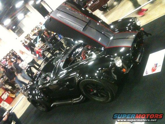 Black sports car with hood open, showing engine and red accents