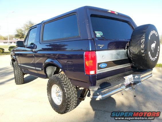 Dark blue Ford Bronco with lifted suspension and off-road tires, seen from rear-three-quarter angle