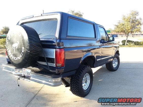 Blue 1995 Ford Bronco, rear view, lifted with spare tire on back
