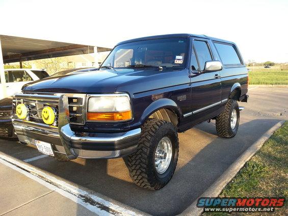 Dark blue Ford Bronco with smiley face fog lights and lifted suspension