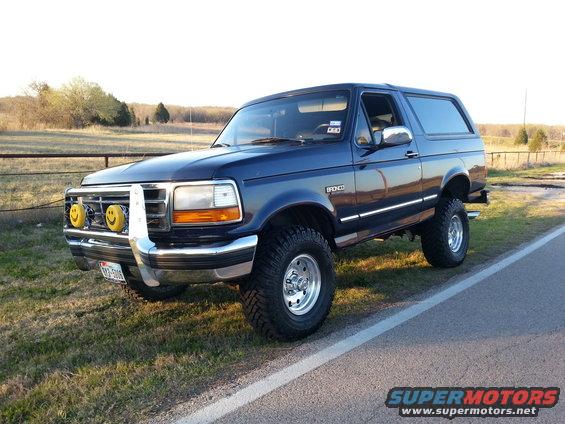 Blue 1995 Ford Bronco with smiley face fog lights and chrome grille guard