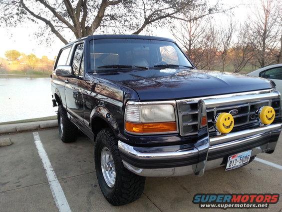 Dark blue 1995 Ford Bronco with smiley face lights and lifted suspension