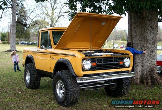 Yellow 1977 Ford Bronco with hood open, front 3/4 view