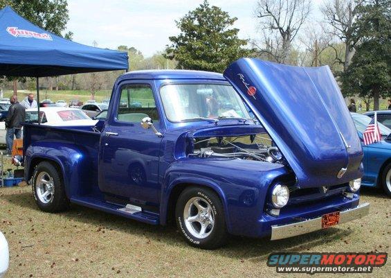 Blue 1955 Ford F-100 pickup truck with hood open, chrome bumper, and aftermarket wheels