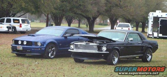 Black 1968 Ford Mustang coupe with hood open, parked next to a blue modern Mustang