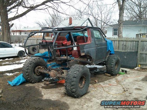 Modified off-road vehicle with roll cage and large tires, viewed from 3/4 front