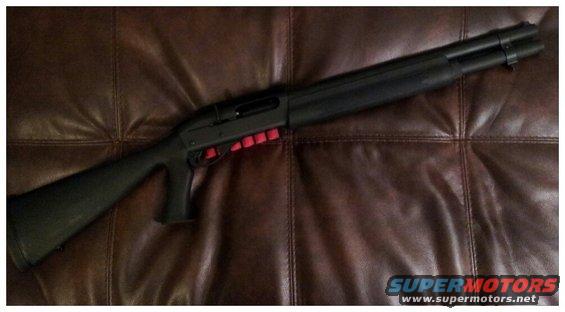 Black shotgun with red shell holder on brown leather couch