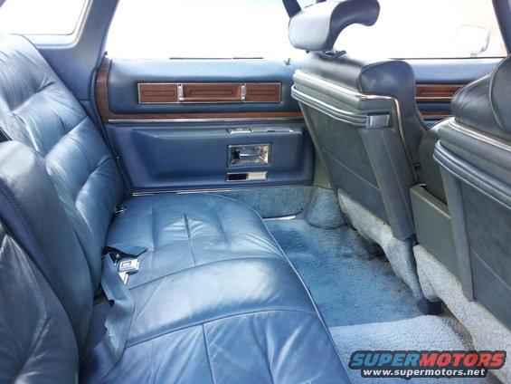 Blue leather rear seats and door panel with wood trim. A seatbelt is visible