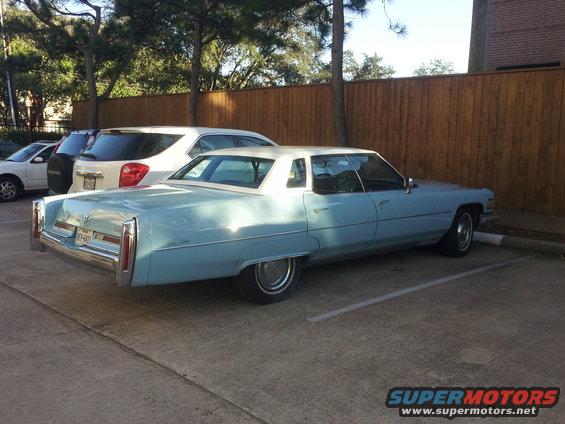 Light blue Cadillac sedan parked next to a white SUV and a white car. The Cadillac has a white roof and chrome trim