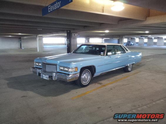 light blue Cadillac coupe parked in a parking garage, white roof, chrome trim