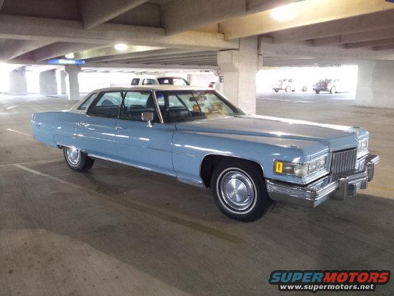 Light blue 1974 Cadillac sedan with a vinyl roof, seen from the front-right in a parking garage