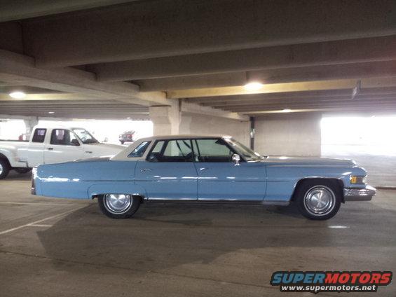 Side view of a light blue 1970s Cadillac sedan parked in a garage