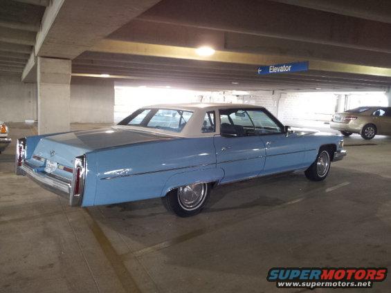 blue Cadillac sedan parked in a garage, another car visible in background