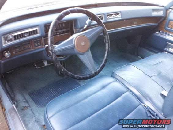 Blue leather interior with a large steering wheel and wood trim dashboard