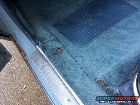 Interior view of worn blue carpet and rubber floor mat