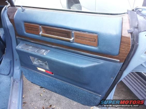 Blue interior door panel with wood trim and chrome accents
