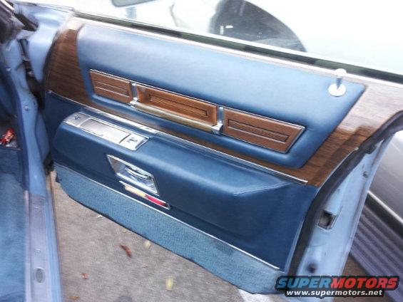Blue interior door panel with wood trim and chrome handle