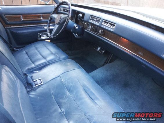 Blue leather interior of a vintage car, showing front seats, dashboard, and steering wheel