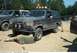 1993 Ford Bronco - A person works on a muddy 1993 Ford Bronco, which is parked next to another vehicle.