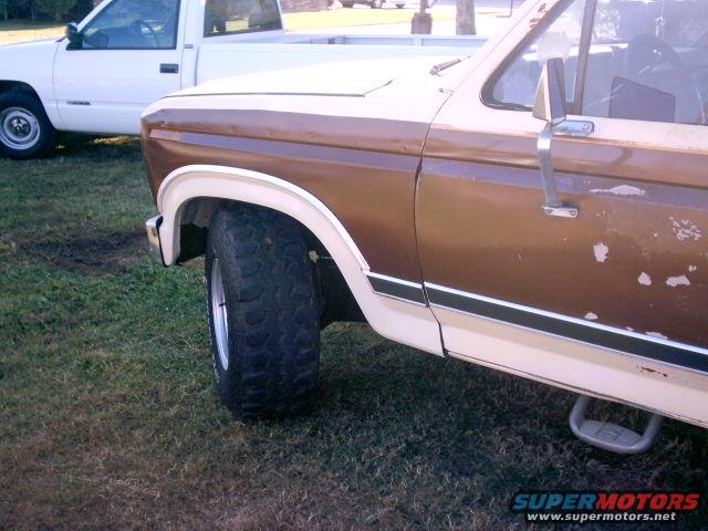 Side view of a brown and white pickup truck with a white pickup truck in the background