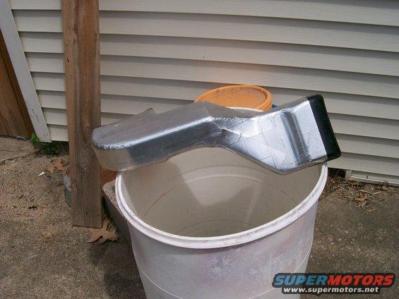 Custom aluminum air intake duct taped together, resting on a white bucket