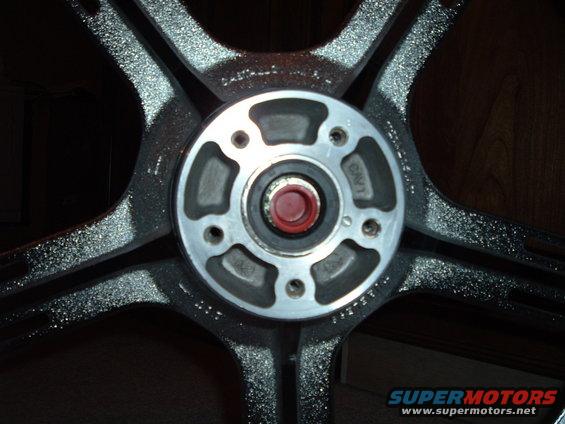 Close-up of a motorcycle wheel hub with five spokes. Text is visible on the hub