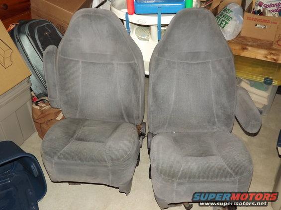 Two grey fabric car seats with corduroy-like texture and armrests, viewed from the front in a storage area