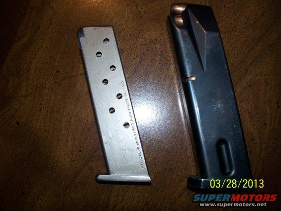 Two gun magazines, one silver and one black, on a wooden surface