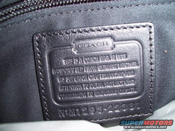 Close-up of a black leather Coach bag label with embossed text and a serial number