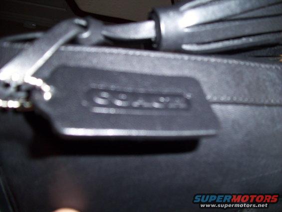 Black leather handbag tag with embossed COACH logo and metal ring