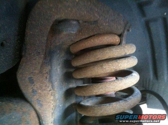 Close-up of a rusty coil spring and suspension components