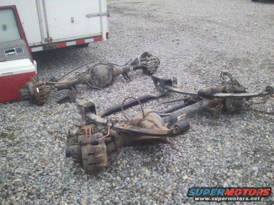 Two vehicle rear axles with brake components and leaf springs on gravel