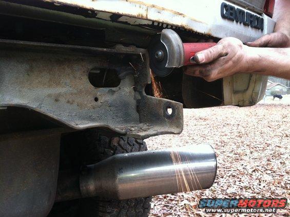 Cutting rusty bumper with angle grinder, Centurion badging visible